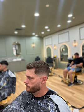 Textured haircut with tapered sides and a trimmed beard at Signature Hair Styles