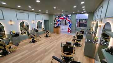Wide view of the Signature Hair Styles interior with sage green walls, gold barber chairs and timber flooring